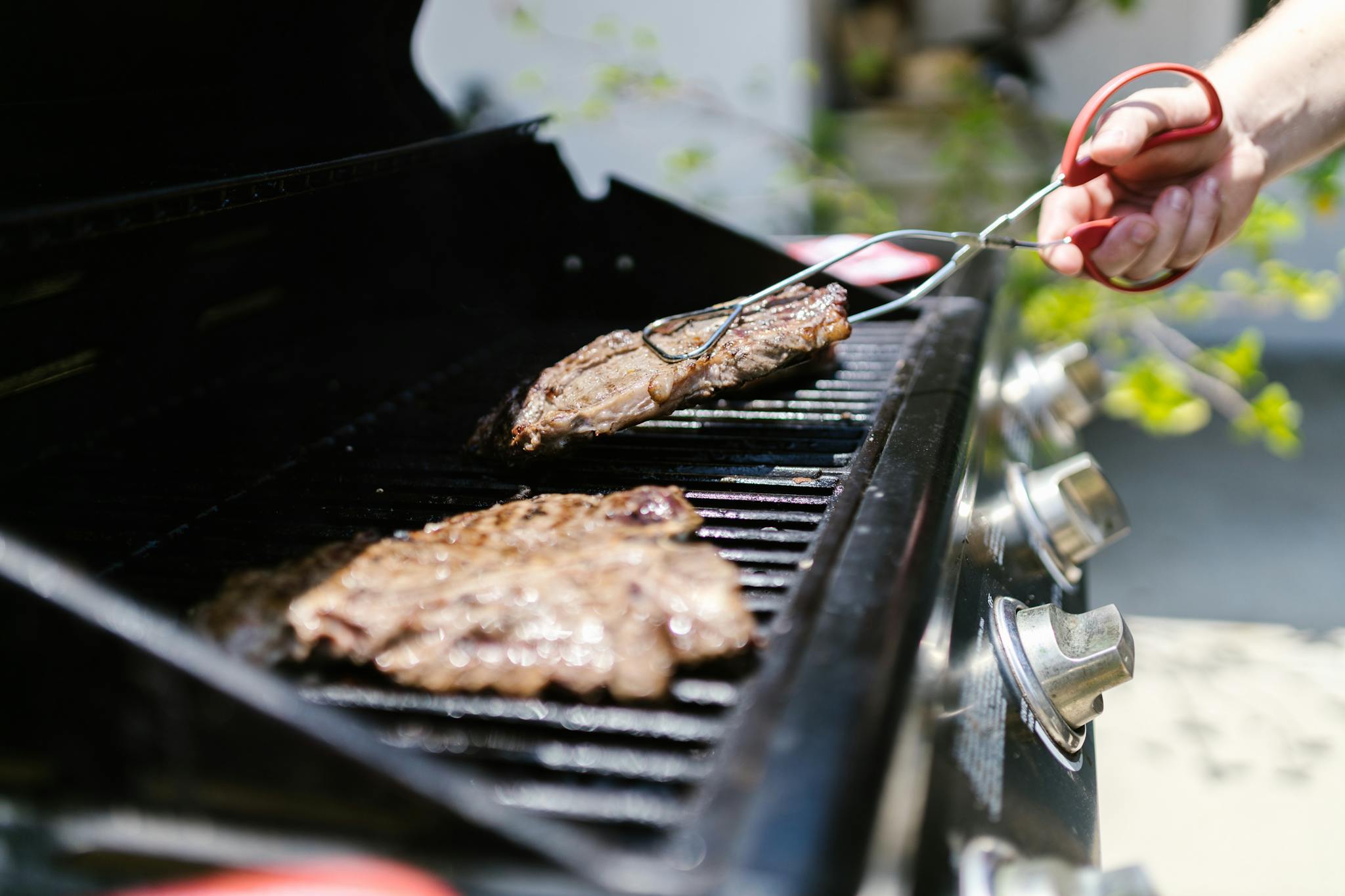Close-up of juicy steaks grilling on a barbecue, perfect for summer cookouts.